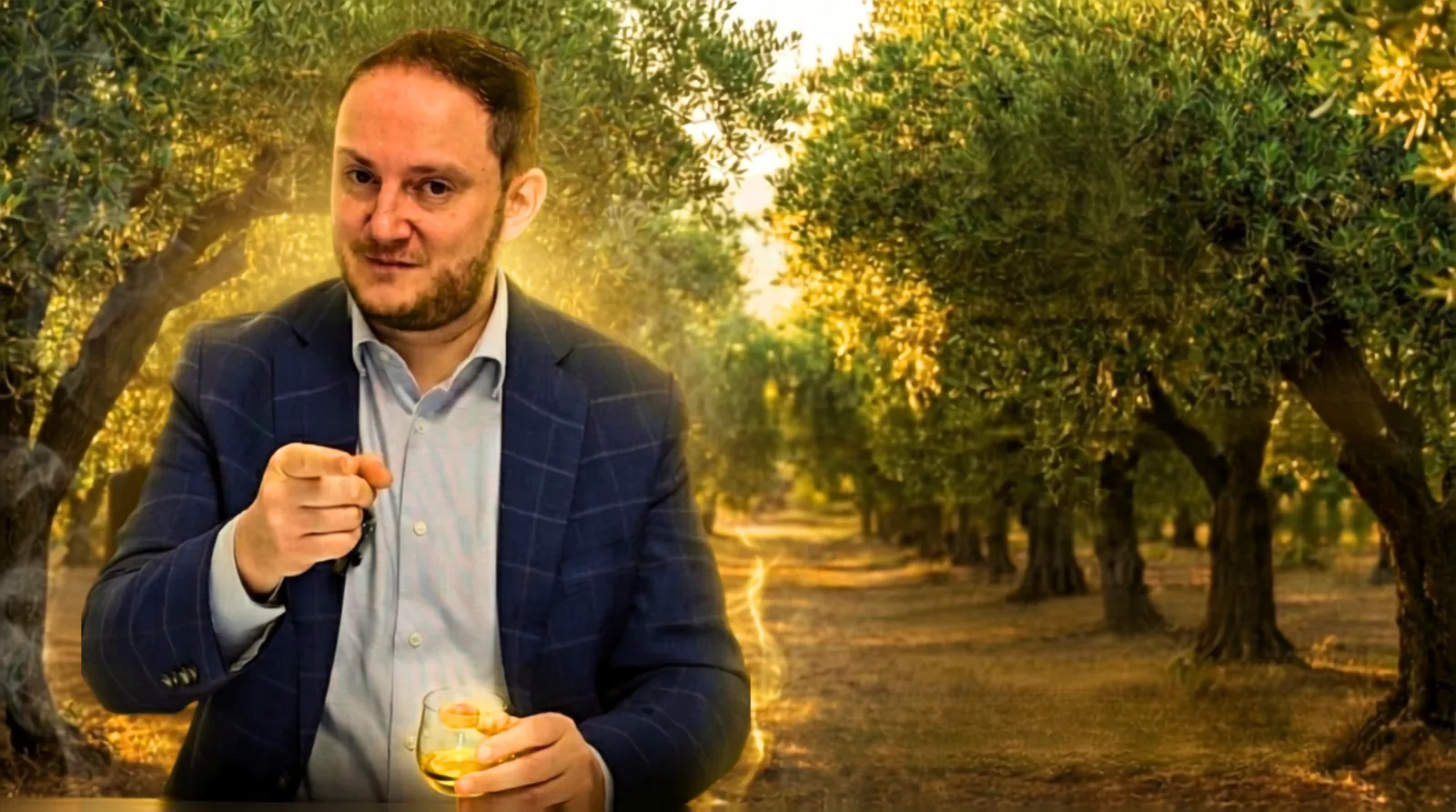 Dario Masciaga tra gli olivi con un bicchiere di olio extravergine